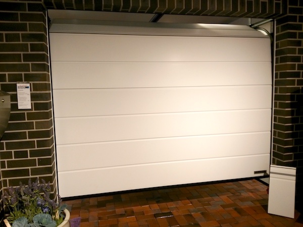 Weißes Sektionaltor mit breiten Sicken, das gerade geöffnet wird